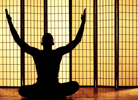 Silhouette of a man meditating and finding a zen momentの写真素材