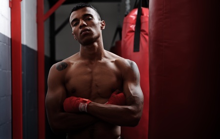 portrait of a fighter training in the gym, punching bags, wrapped fists and bare chestの写真素材