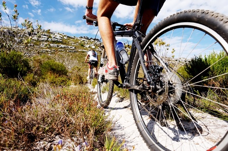 Wide angle view of a cyclist riding a bike on a nature trail in the mountains. two people living a healthy lifestyle Wide angle view of a cyclist riding a bike on a nature trail in the mountains. two people living a healthy lifestyle
