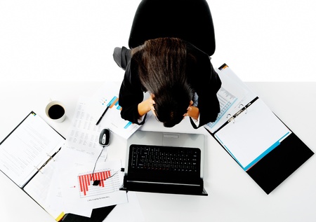 overwhelmed businesswoman holds her head in her hands and is stressed.の写真素材