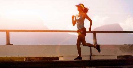 runner training at sunset, silhouette of fitness marathon woman with lens flare and actionの写真素材