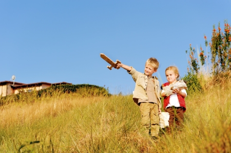 Young children playing explorers with treasure map and wooden sword. little adventure seeking kids having fun outdoors in the back yardの写真素材