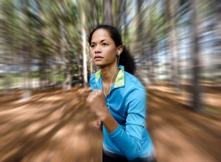 Portrait of a runner listening to music on headphones while running outdoors in a forest. healthy wellness fitness lifestyle. の写真素材