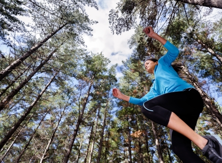 low angle view of runner jumping and running in forest. healthy active lifestyle の写真素材