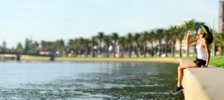 Panorama of suburban scene with athlete resting and drinking alongside a riverの写真素材