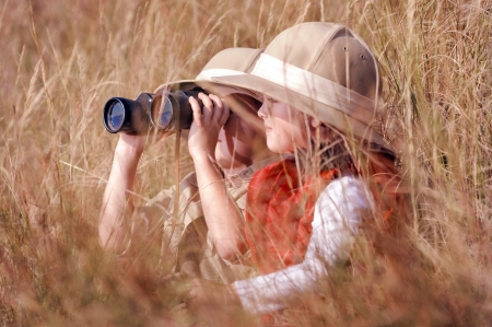 Children brother and sister playing outdoors pretending to be on safari and having fun together with binoculars and hatsの写真素材