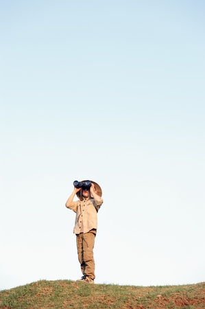 Young boy child playing pretend explorer adventure safari game outdoors with binoculars and bush hatの写真素材