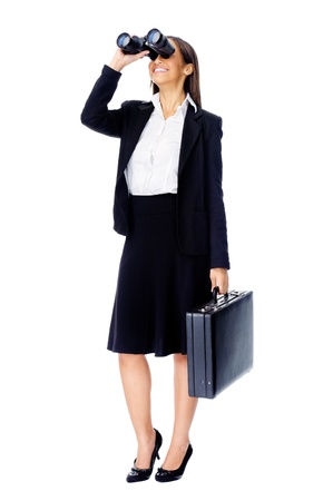 Business vision concept with businesswoman looking through binoculars while wearing a suit and with briefcase isolated on whiteの写真素材