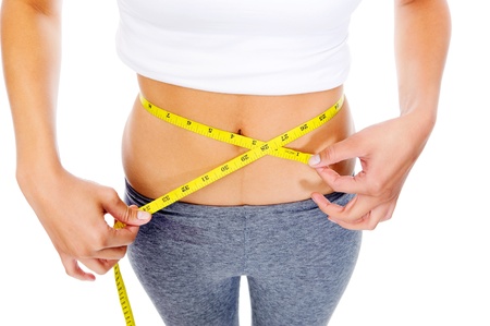 Slim woman measuring her weightloss with tape and looking at her waist. dieting concept. isolated on whiteの写真素材