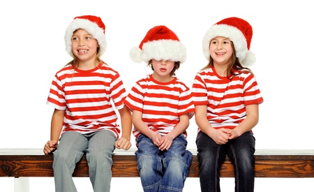 Christmas children having fun with xmas hats, gift box and matching t-shirts isolated on white backgroundの写真素材