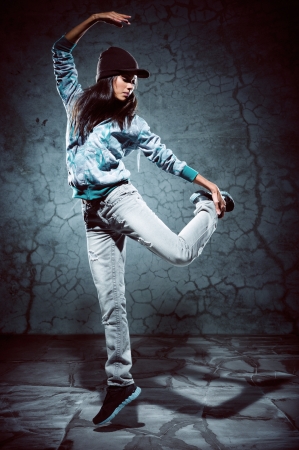urban hip hop dancer with grunge concrete wall background texture jumping and dancing with hoodieの写真素材