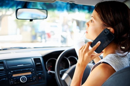 businesswoman driving car and talking on cell phone concentrating on the road