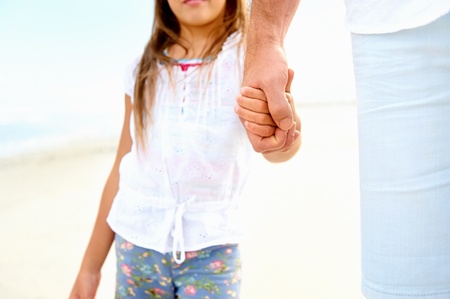 Father and daughter holding hands on the beach together happy and loving vacationの写真素材