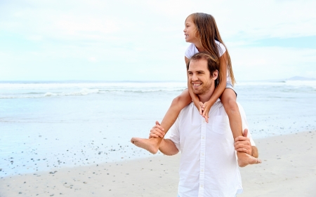 loving father with daughter on shoulders walking on the beach carefree and happyの写真素材