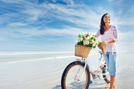 woman with bicycle and flowers in basket smiling carefree and happyの写真素材