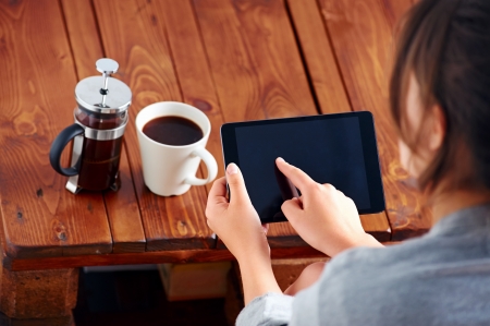 Young woman uses tablet while relaxing at home with coffee on the sofa couchの写真素材