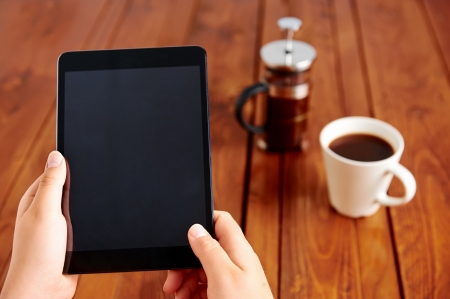 Young woman uses tablet while relaxing at home with coffee on the sofa couchの写真素材