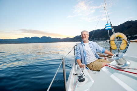 carefree happy sailing man portrait of mature retired man on ocean boat at sunriseの写真素材
