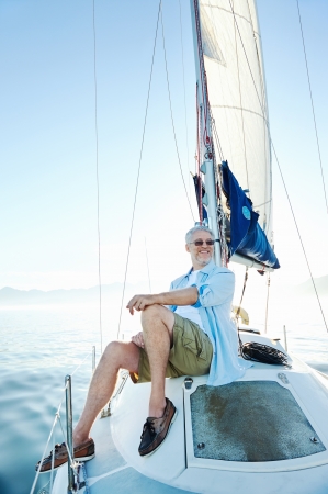 relaxing man sitting on boat sailing on ocean happy and carefreeの写真素材