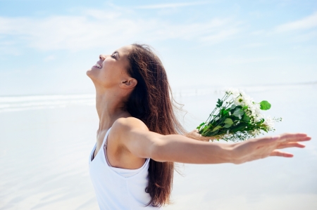 woman with arms out freedom girl on beach with flowers in summerの写真素材