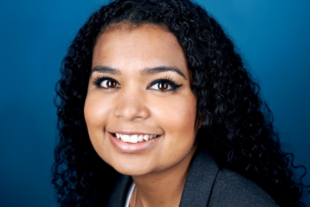 natural smiling portrait of mixed race  real woman on blue backgroundの写真素材