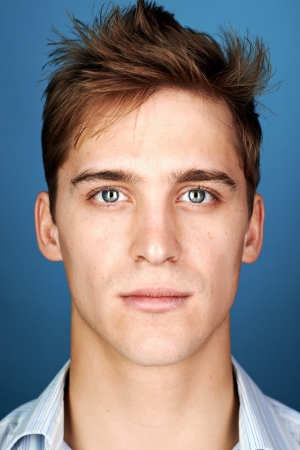 portrait of real man face looking at camera on blue background