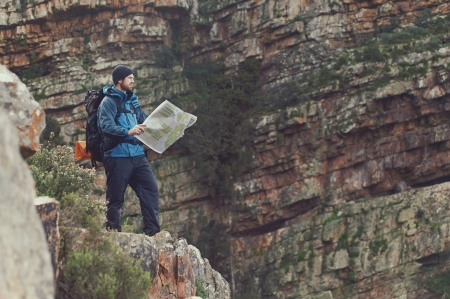 Man with map exploring wilderness on trekking adventureの写真素材