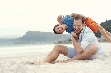 Fatehr and son playing at beach together portrait fun happy lifestyleの写真素材
