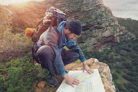 Lost hiker with backpack checks map to find directions in wilderness areaの写真素材