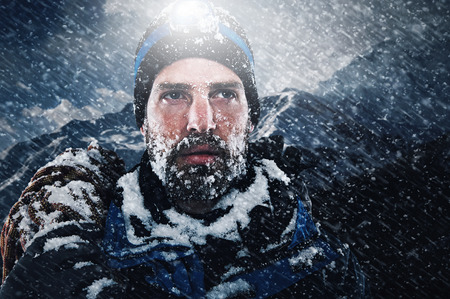 adventure mountain man in snow blizzard looking on with determination and courage