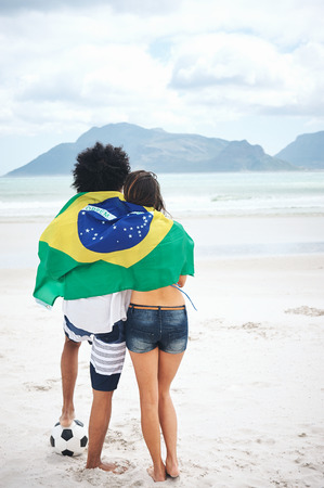 Brazil soccer fans stand on beach together with flag for world cup with ballの写真素材