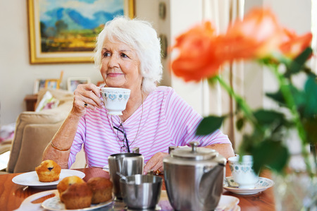 A content old lady enjoying some tea and a muffinの写真素材