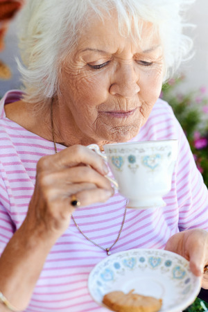 A female pensioner about to sip from her cup of teaの写真素材