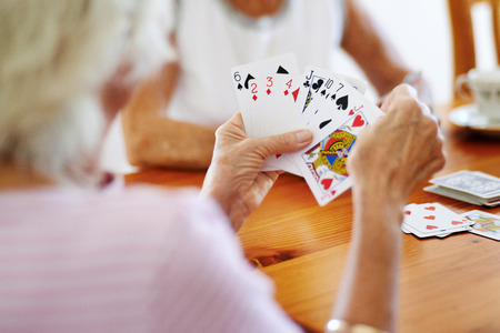 Close up shot of two elderly friends playing a card game