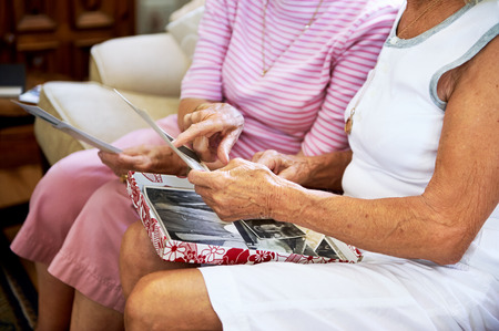 Cropped shot of elderly women feeling nostalgic and looking at old photographs