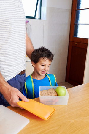 happy young boy with dad and healthy food apple in lunch box for schoolの写真素材