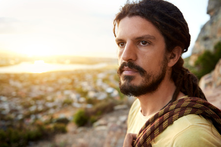 Man on mountain holding climbing rope preparing to climb up the mountain and looking at the viewの写真素材