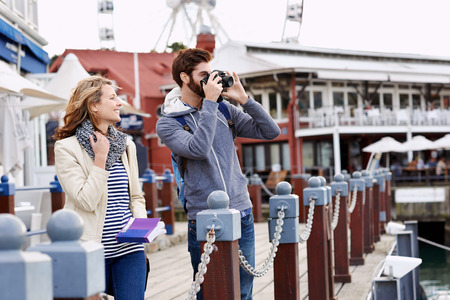 young couple taking pictures on holiday at tourist attractionの写真素材