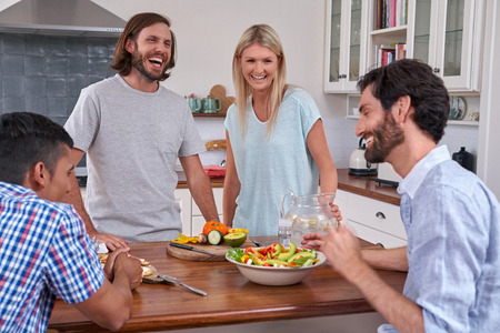 group of friends laughing happy with salad in kitchen