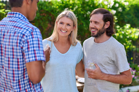 friends chatting outdoors at garden party gathering with cocktail wine drinks