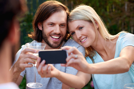young couple taking selfie photo pictures with mobile cellphone camera outdoor garden party