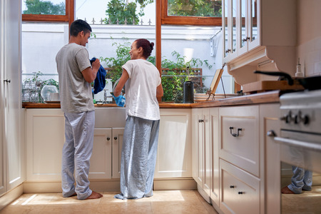 young woman washing dirty dishes together in kitchenの写真素材