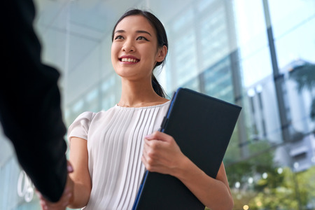 beautiful asian chinese business woman shaking hands in modern city work office