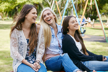 young teen girls playing relaxing together outdoors in playground park laughingの写真素材