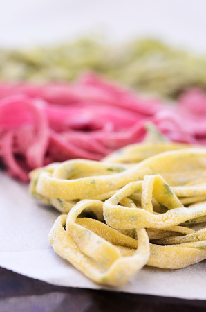 Close up of raw home hand made fresh pasta with variety of flavours, beetroot, herb, spinachの写真素材