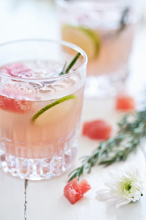 Refreshing cool cocktail mocktail drink decorated with lime slices,watermelon and rosemaryの写真素材