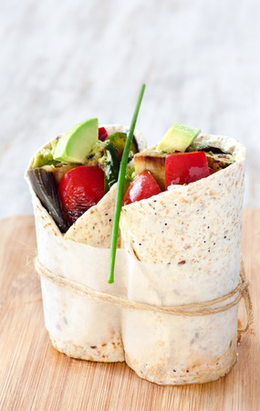 Healthy vegetarian vegan tortilla wraps with roasted vegetables like aubergine eggplant, red bell peppers, avocadoの写真素材
