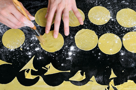 Hands brushing egg whites on raw pasta dics in prepartion for totellini or ravioli stuffingの写真素材