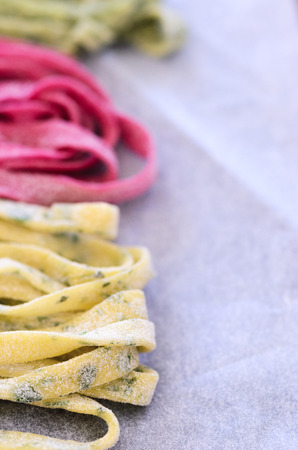 Close up of raw home hand made fresh pasta with variety of flavours, beetroot, herb, spinachの写真素材