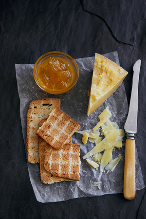 Cheese and crackers served on waxed paper and slate with jamの写真素材